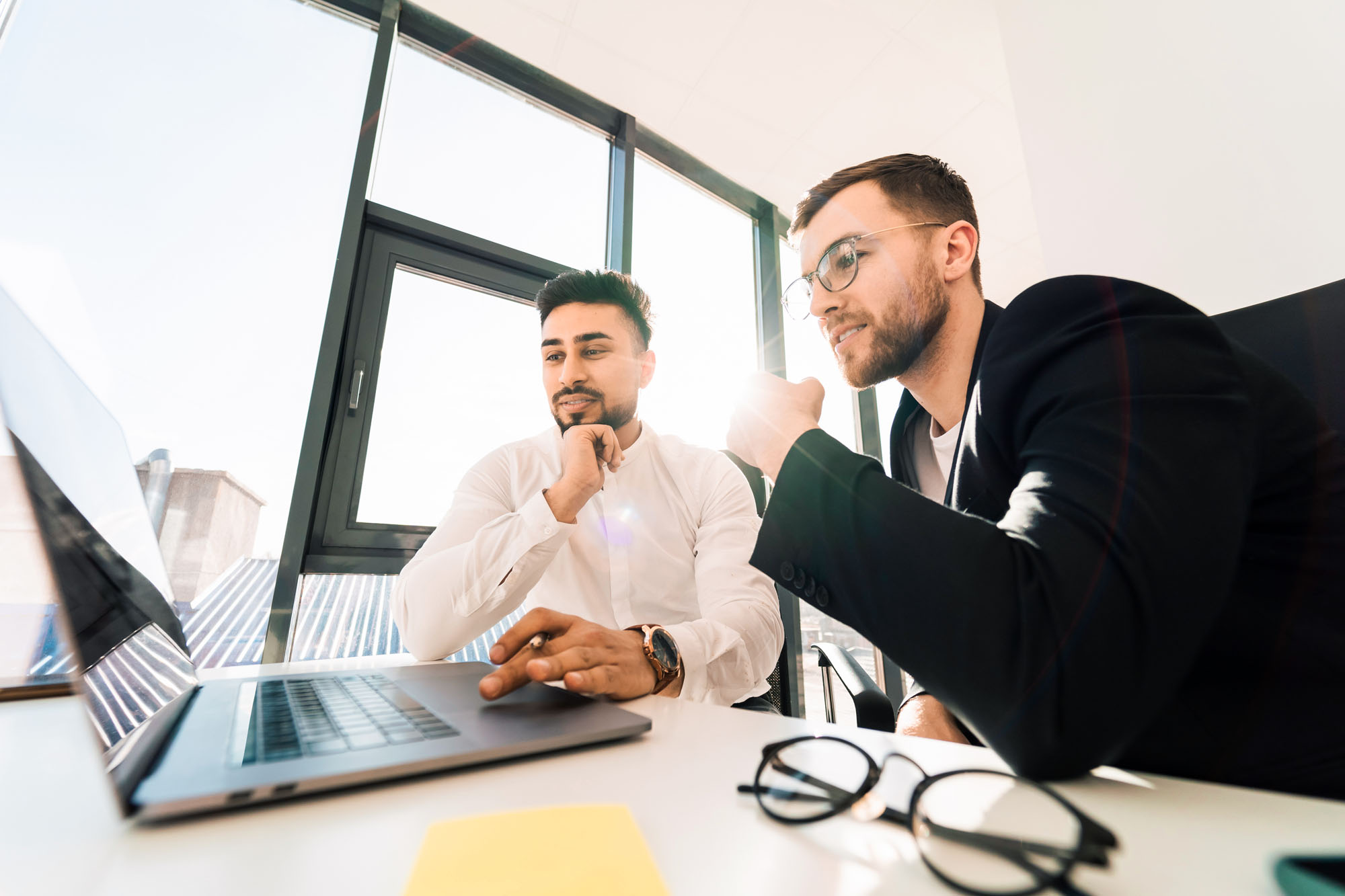 Two employees of software development company are working on startup using laptop